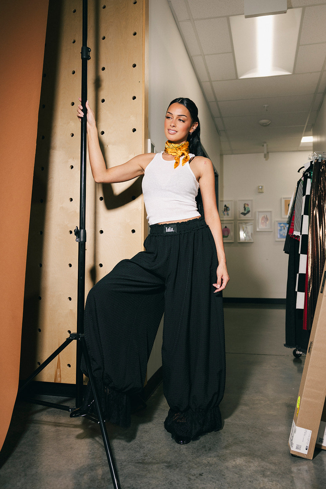 Woman posing next to a backdrop wearing black bloomer pants.