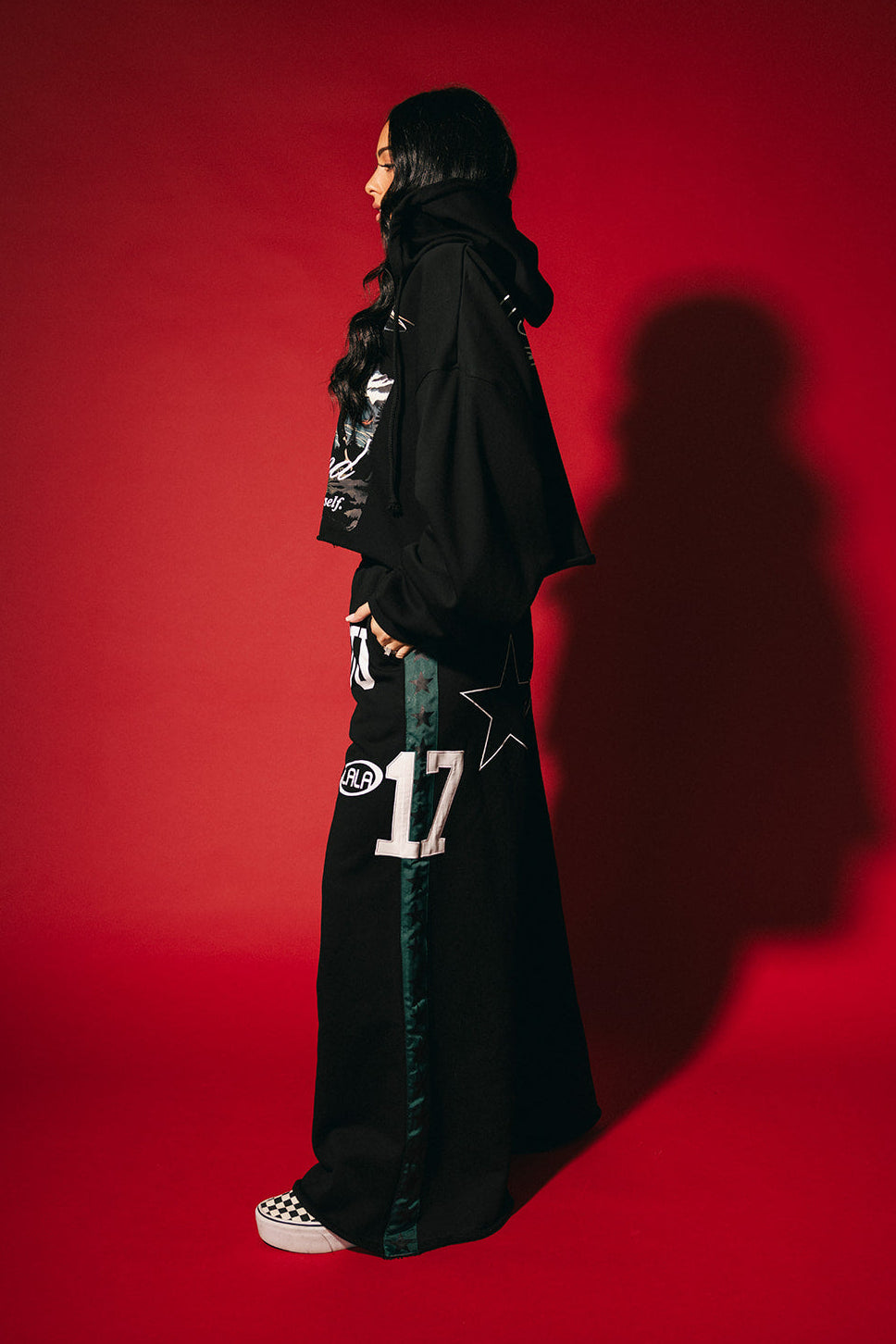 Person wearing a black outfit with star and number designs against a red background