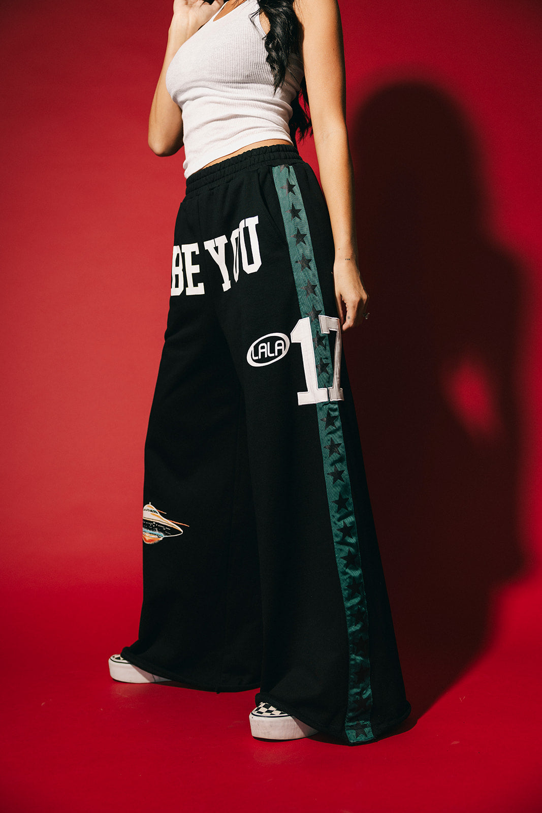 Person wearing black pants with 'BE YOU' branding on a red background