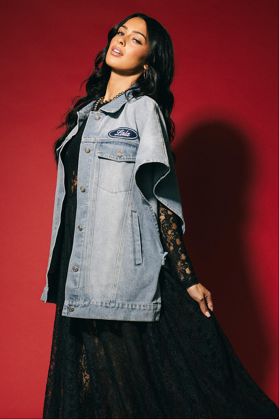 Woman wearing a denim jacket with a brand logo on a red background