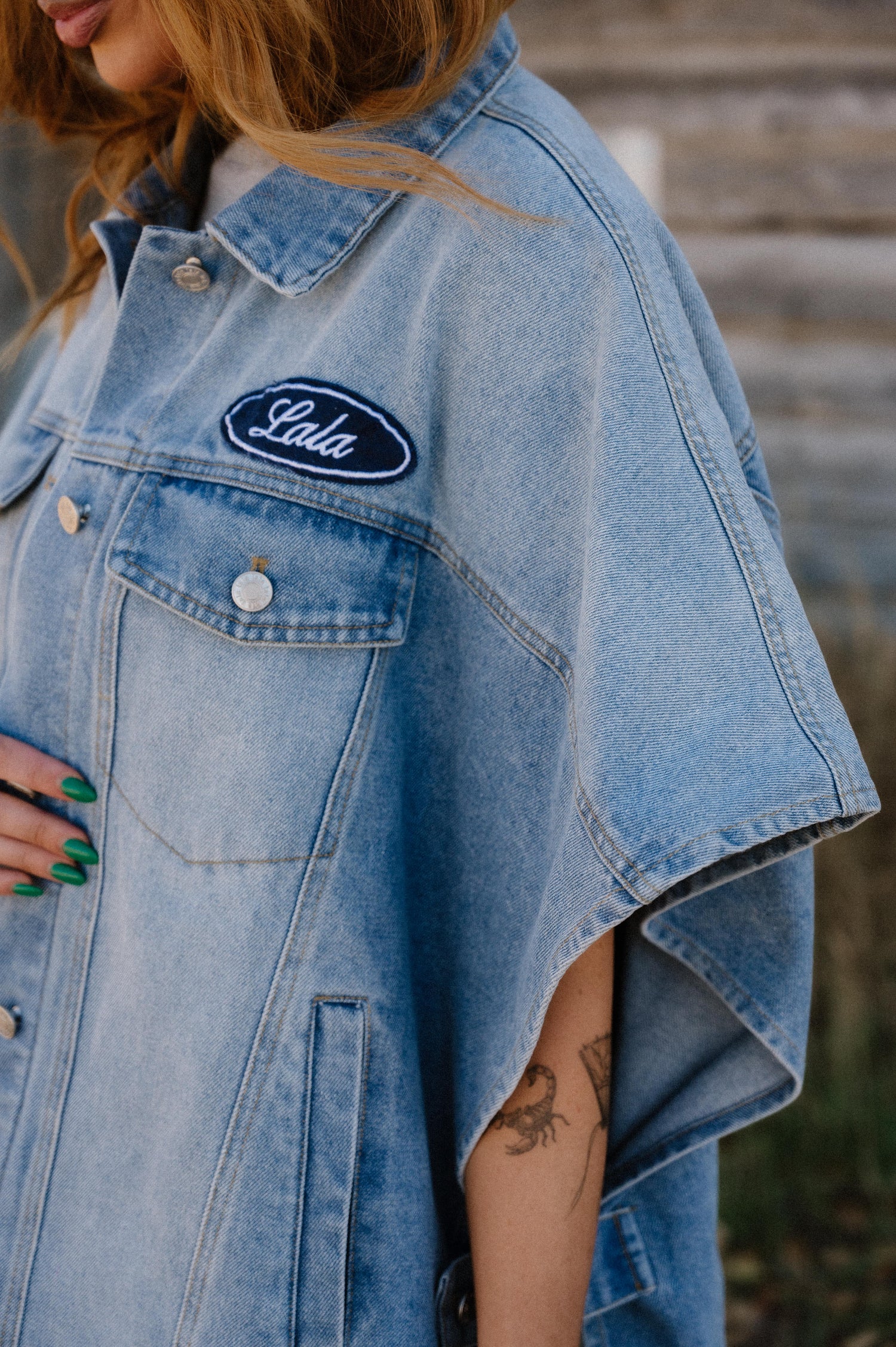 Denim jacket with 'Lola' logo worn by a person, blurred background