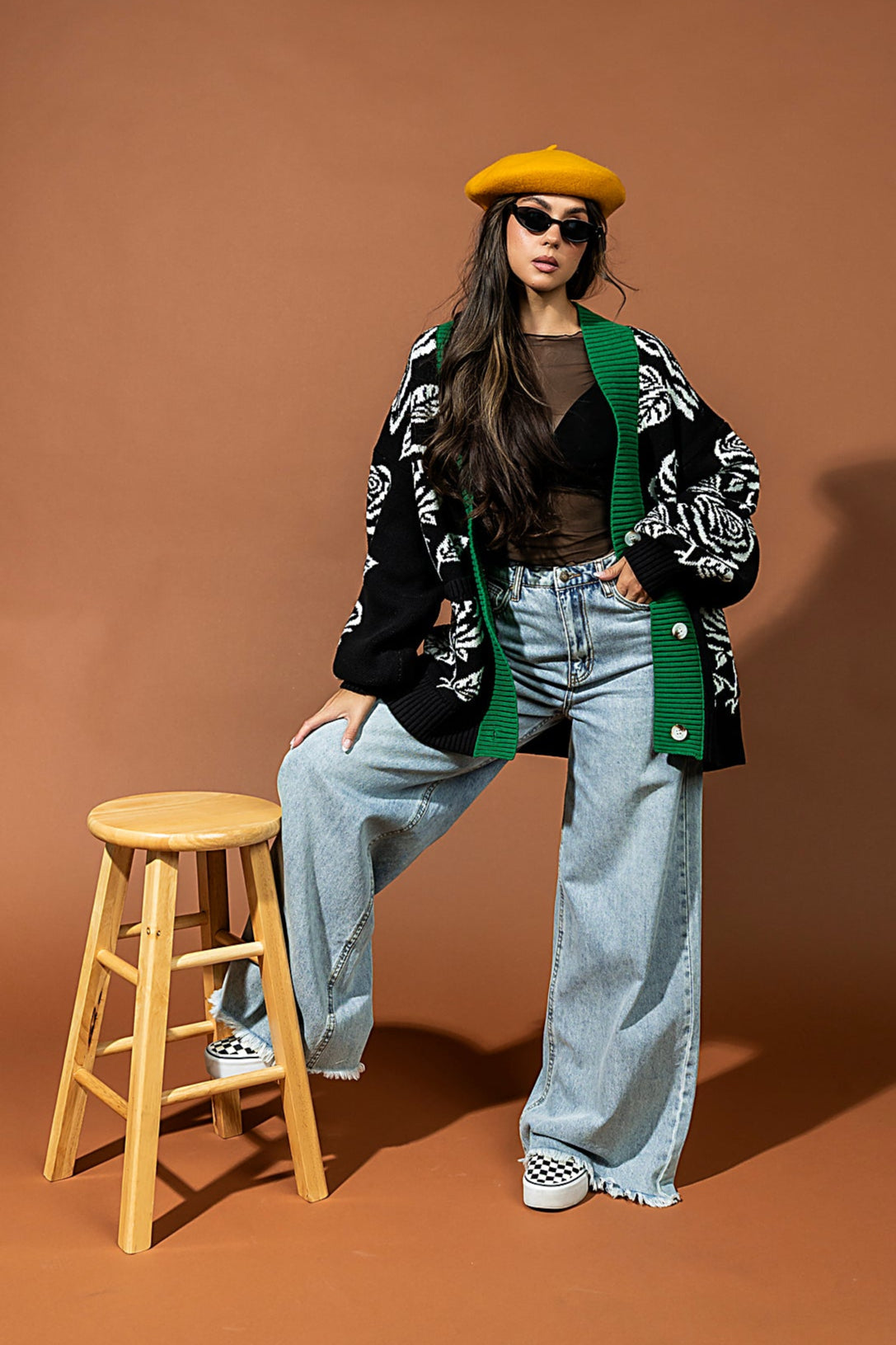 Person posing on a stool against a brown backdrop