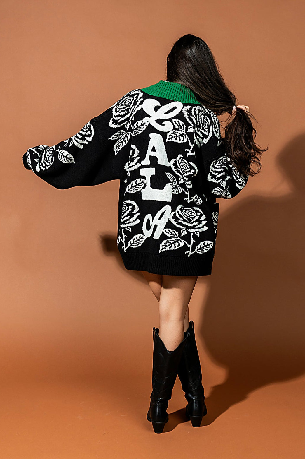 Person wearing a black jacket with white designs on a brown background