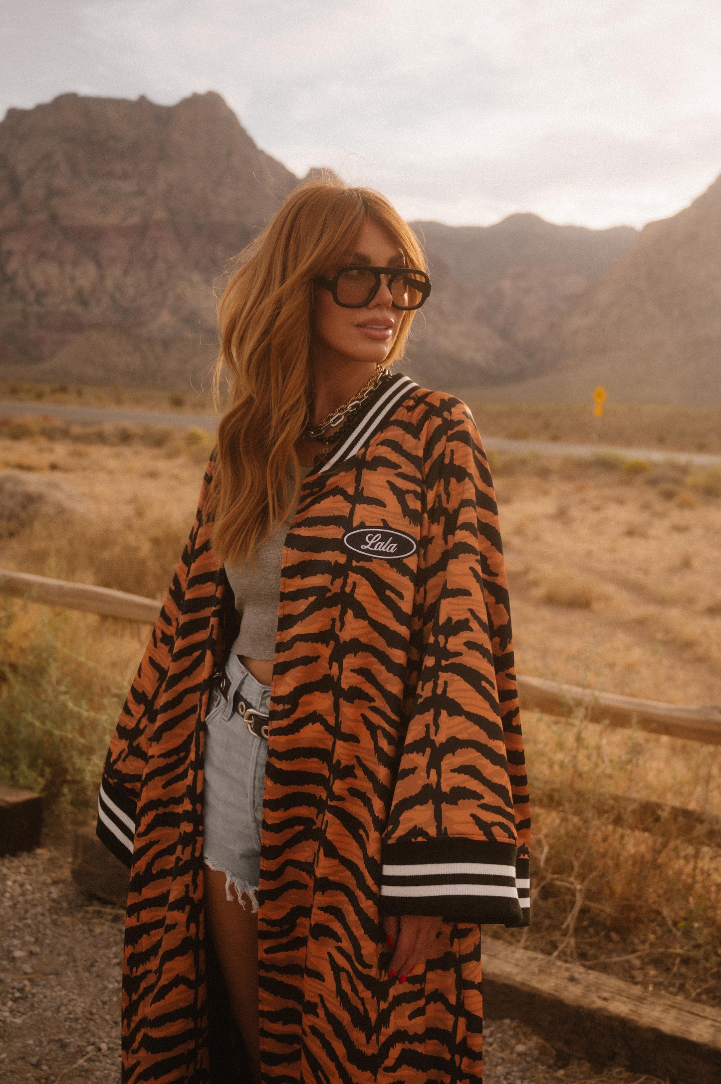 Person wearing a tiger-striped robe with a logo in a desert setting