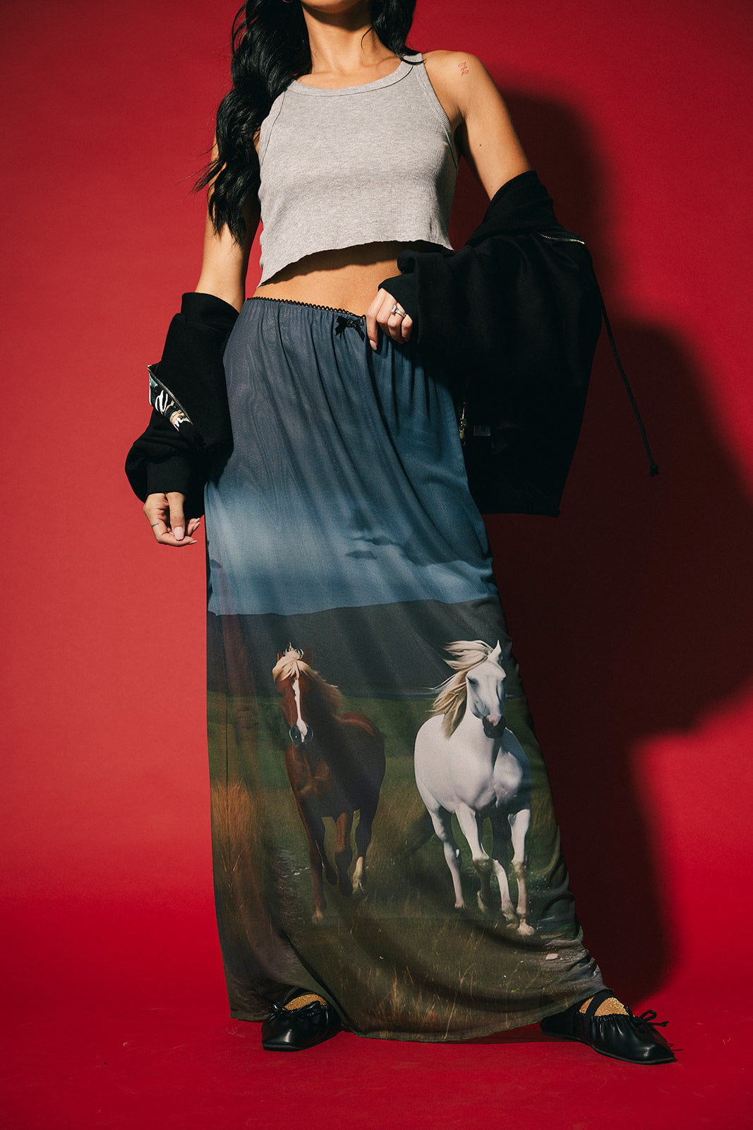 Person wearing a long dress with horse print against a red background