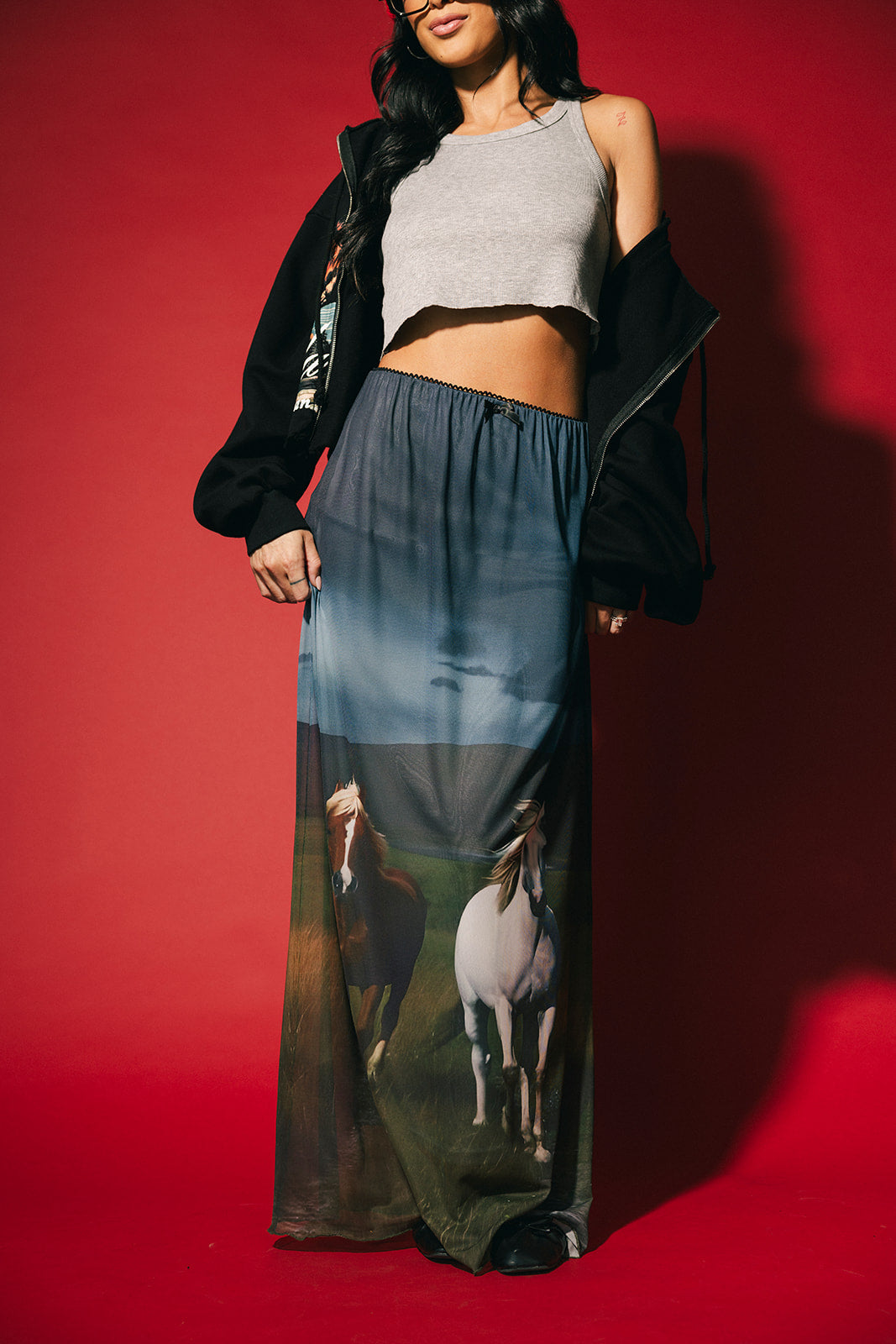 Woman wearing a long dress with horse print against a red background
