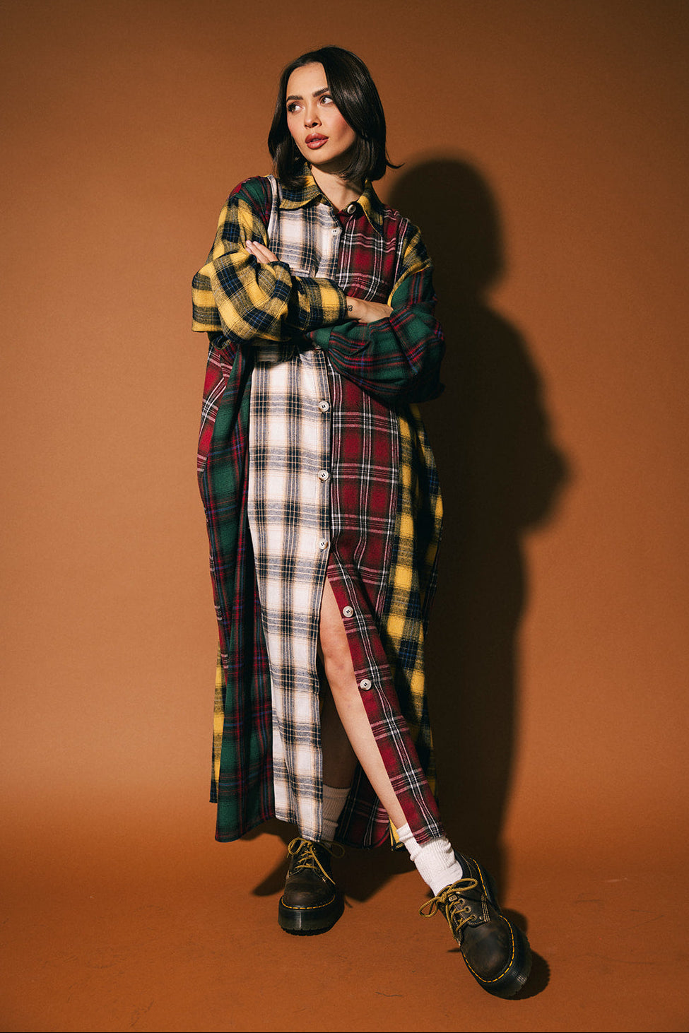 Woman wearing a long patchwork plaid dress against a brown background