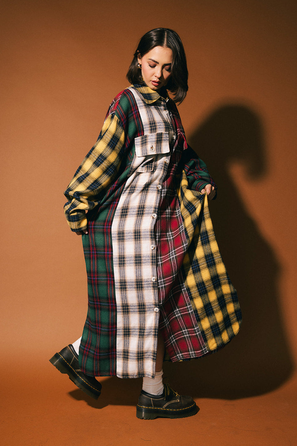Person wearing a long patchwork plaid dress with a brown background