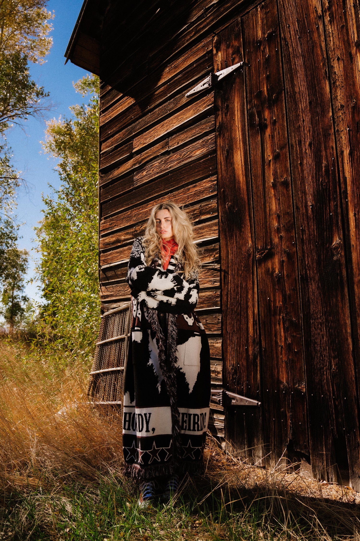 Woman standing in front of a wooden building with trees in the background