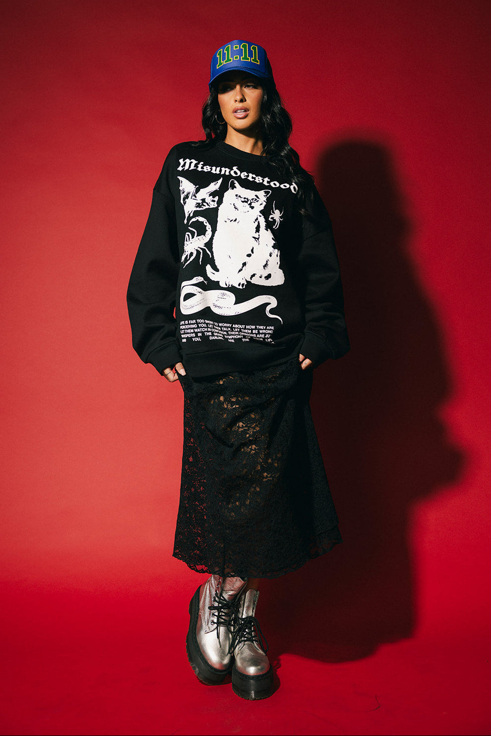 Person wearing a black hoodie with white graphics and text, standing against a red background