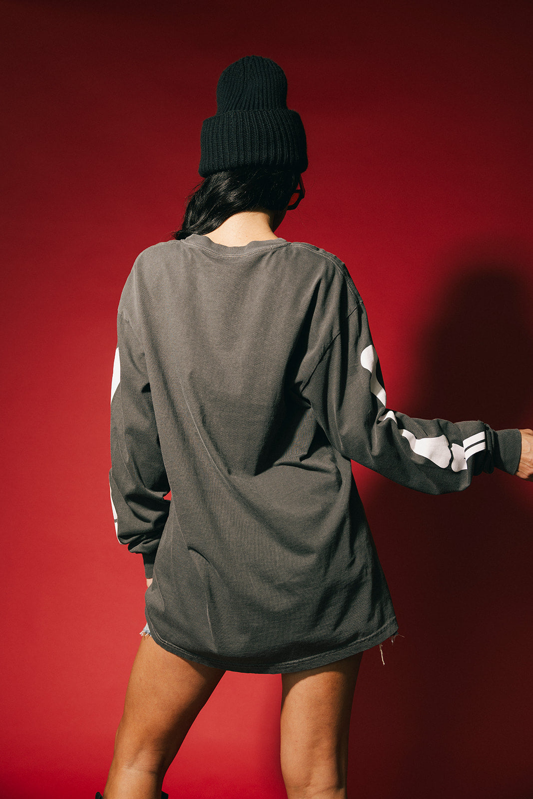 Person wearing a gray long-sleeve shirt with white accents against a red background