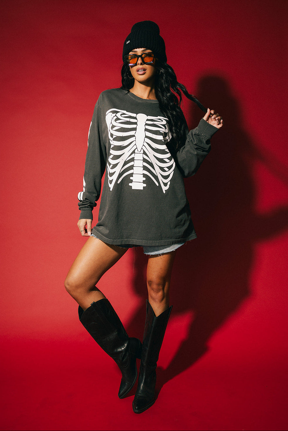Person wearing a dark long-sleeve shirt with a skeleton design on a red background