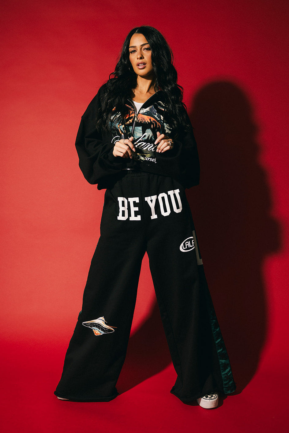 Person wearing a black outfit with 'BE YOU' text on a red background