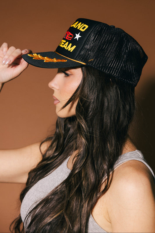 Woman wearing a black cap with text and graphics on a brown background