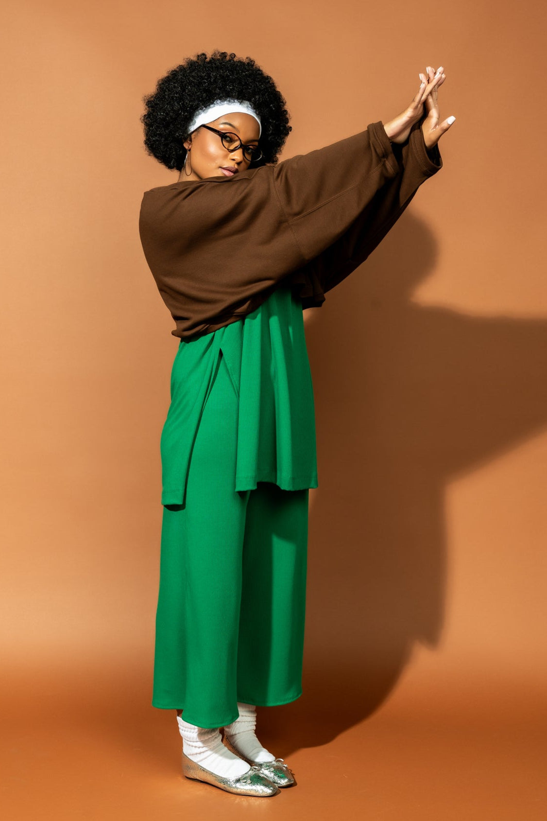 photo of girl wearing green ribbed matching set. The top is long and oversized with high side slits. Pants are cropped and wide leg with an elastic waistband.