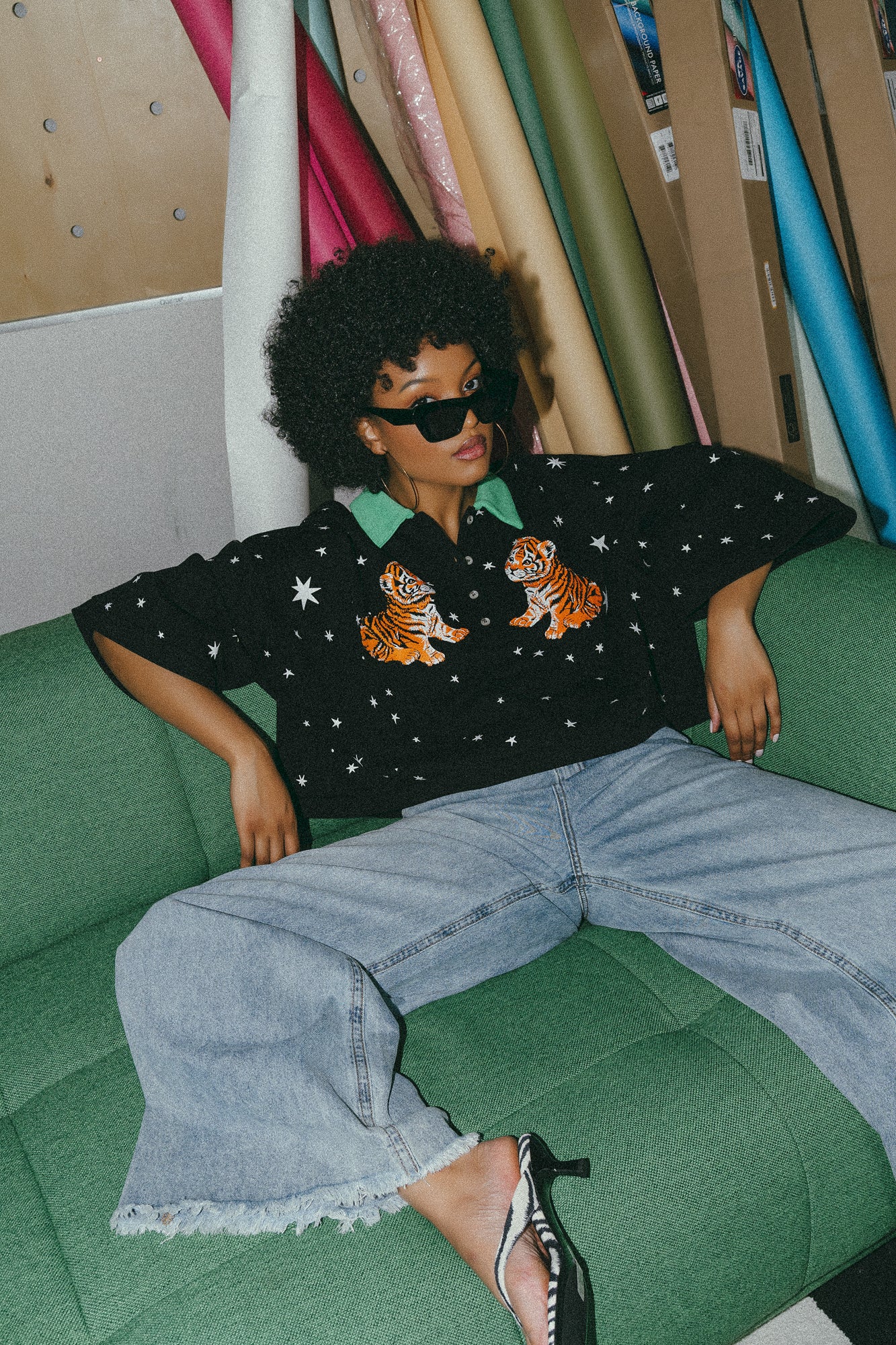 photo of girl wearing black cropped polo with green collar and white stars all over with baby tigers on the front and a baby tiger on the back words that say "made of stardust"