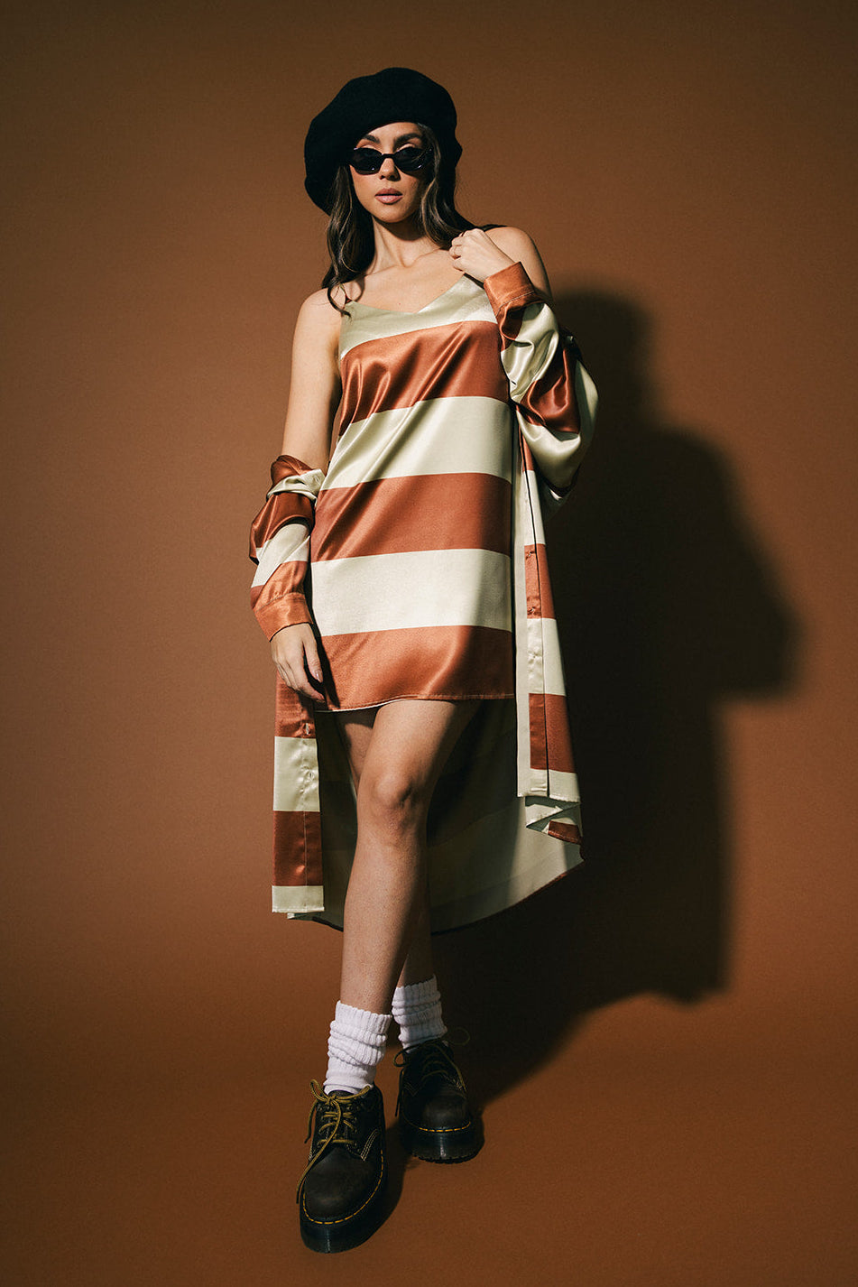 Woman wearing a striped dress with a matching duster against a brown background