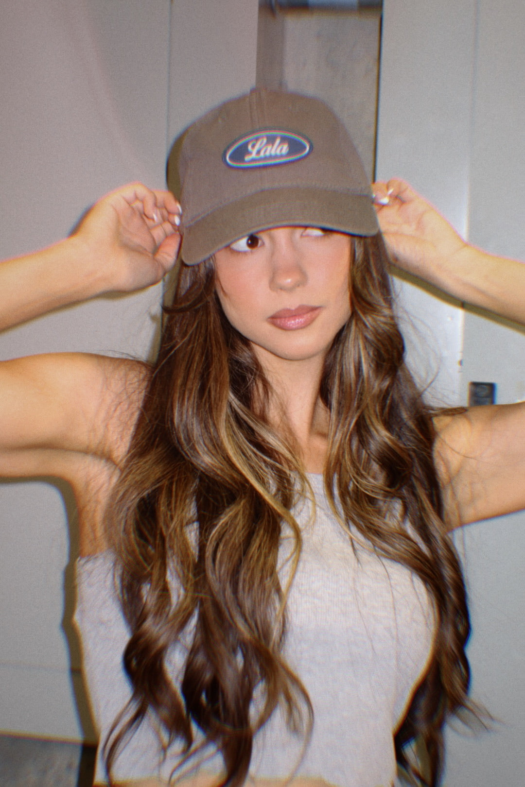 Woman wearing a cap with a visible brand logo indoors.