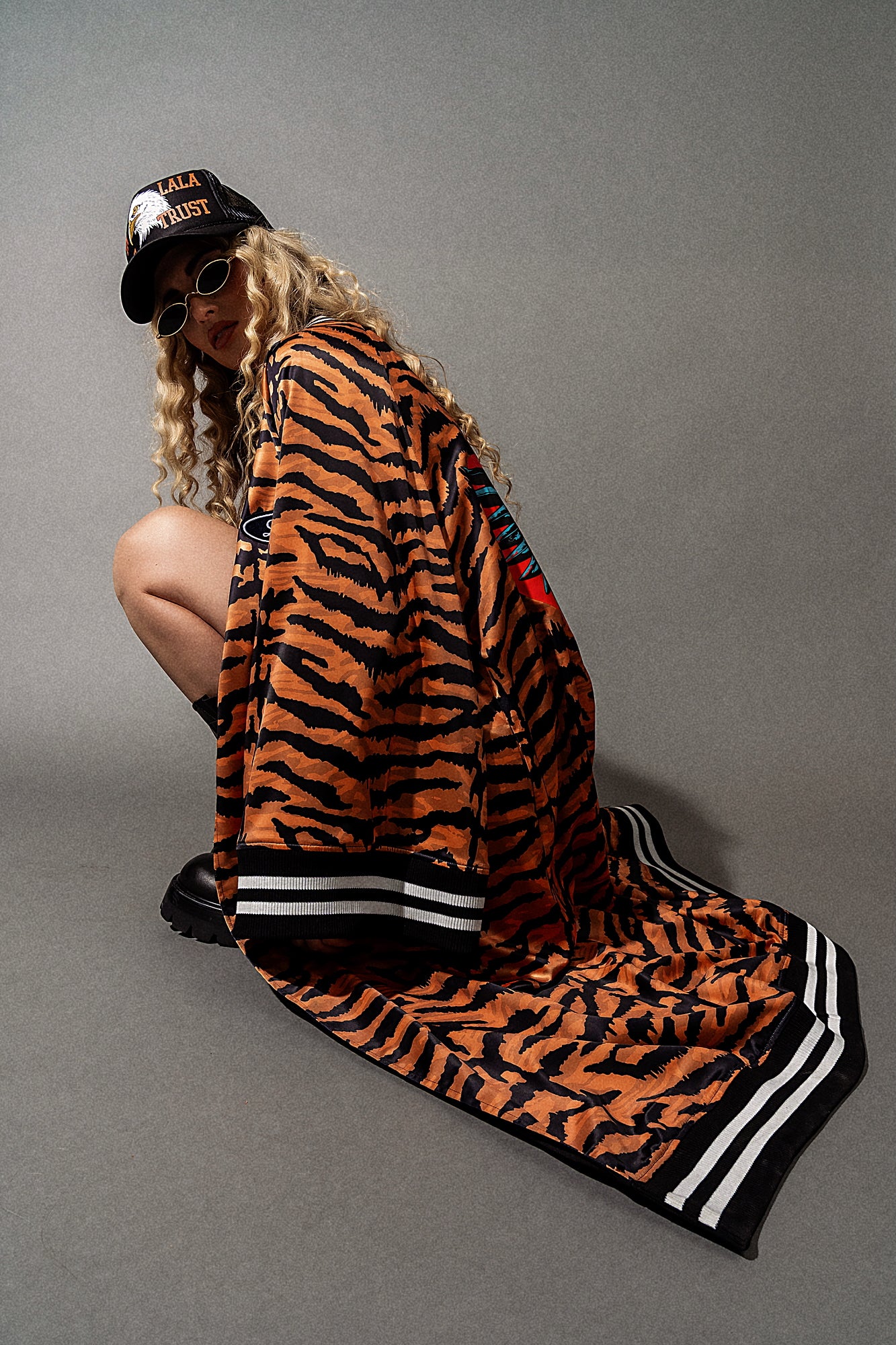 Person wearing a tiger-striped jacket and cap on a gray background
