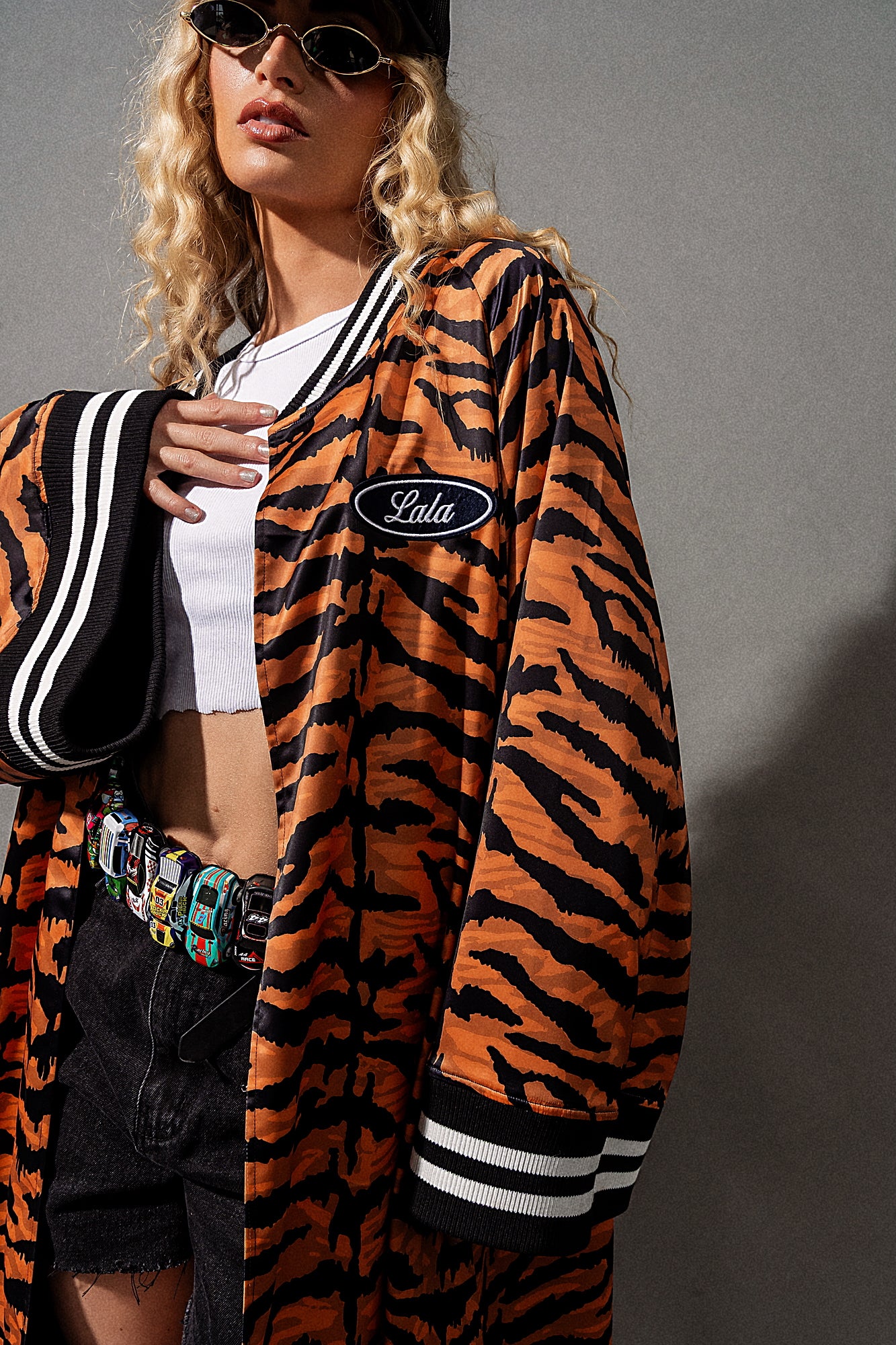 Person wearing a tiger-striped jacket with a brand logo on a gray background