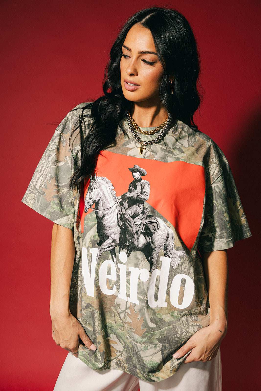 Woman wearing a camouflage shirt with a graphic and the word 'Weirdo' on a red background