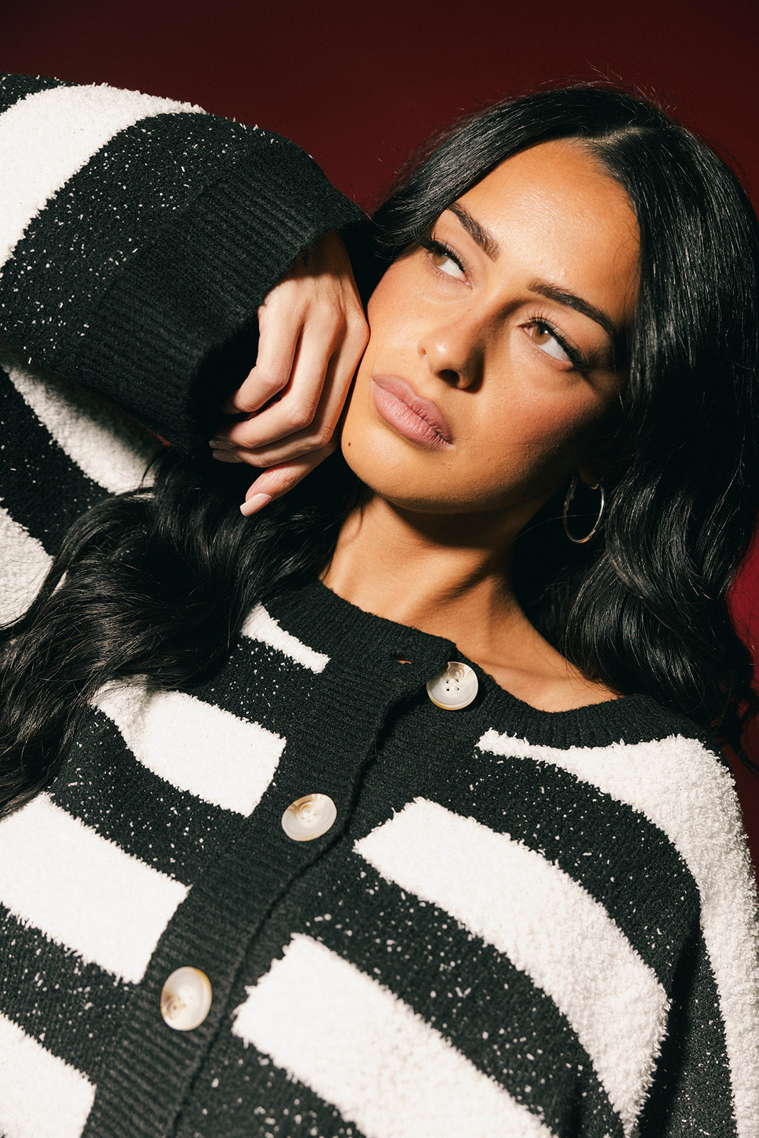 Woman wearing a black and white striped cardigan with a dark background