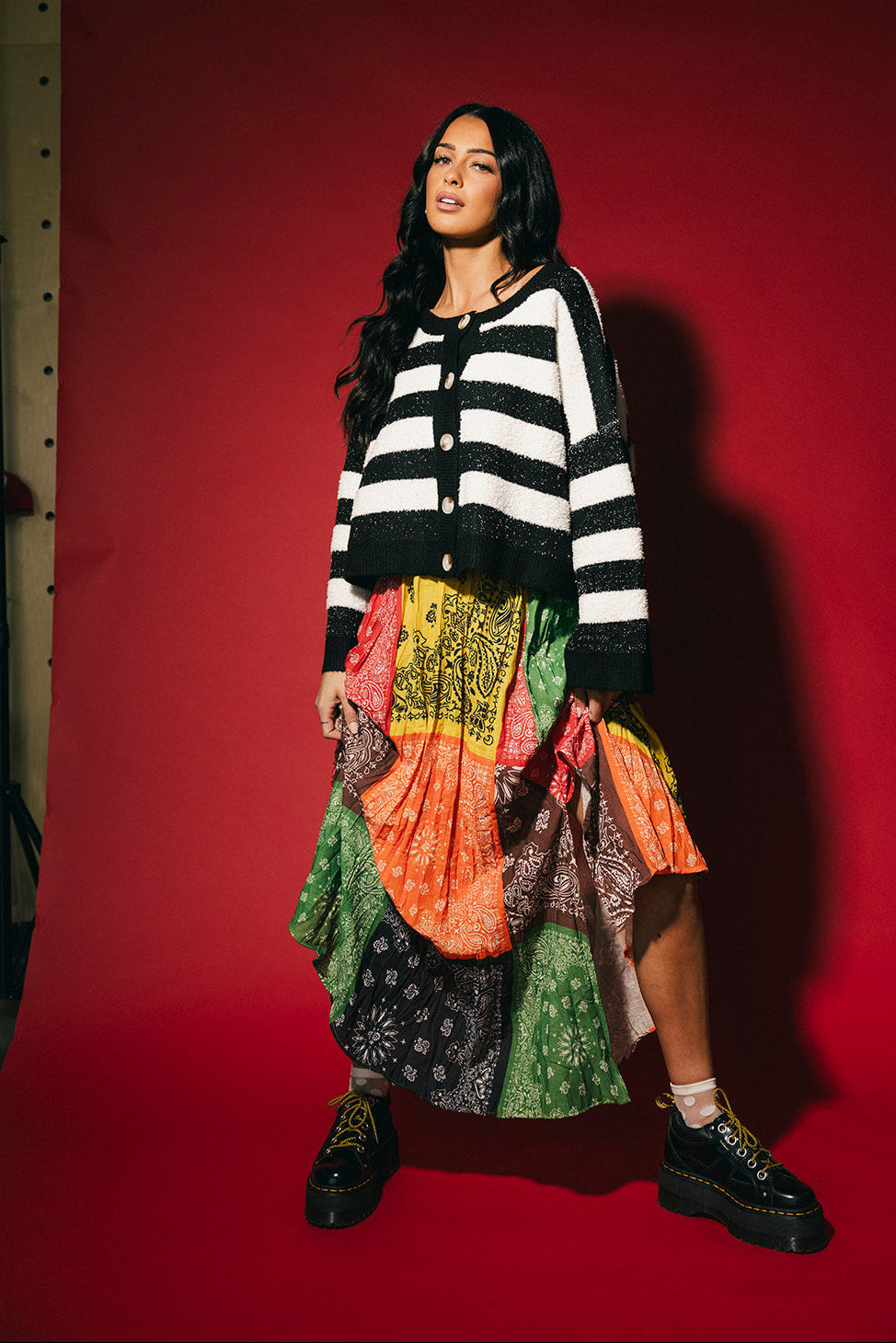 Woman wearing a black and white striped boxy cardigan against a red background