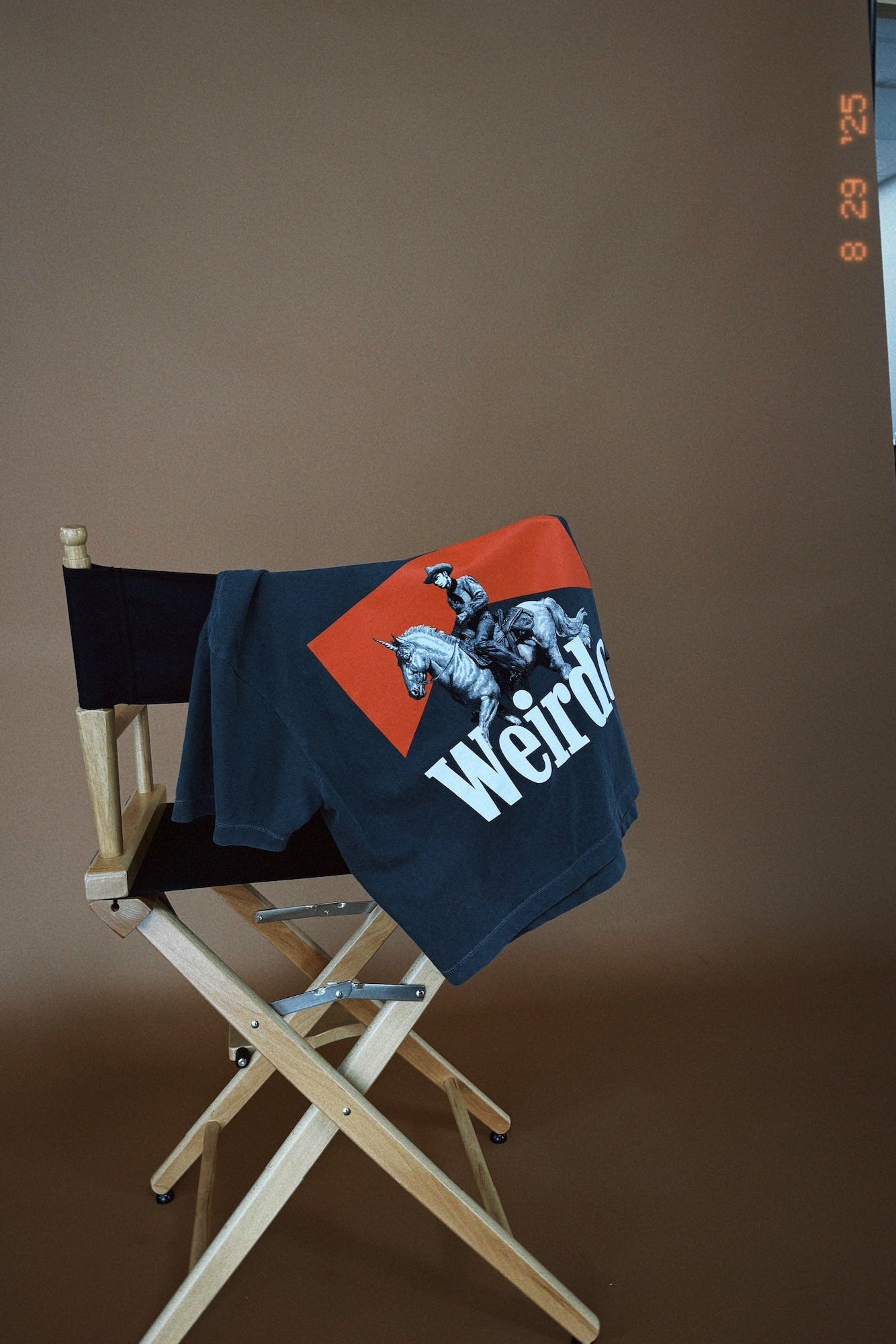 Grey t-shirt with red and white graphic on a wooden director's chair against a brown background
