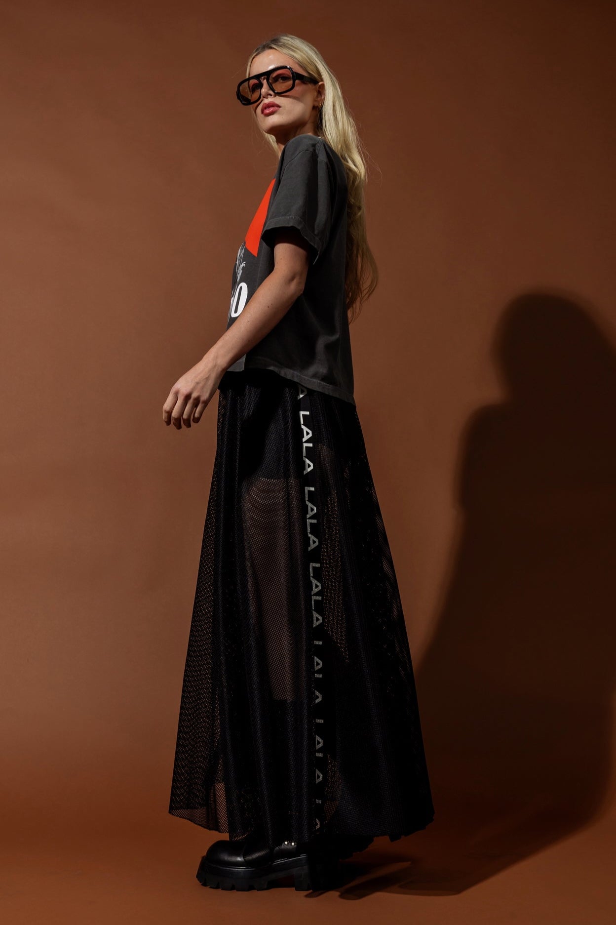 Woman wearing a black outfit with branding on a brown background