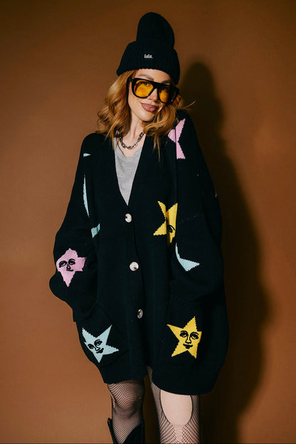 Person wearing a black cardigan with colorful stars and moons on a brown background