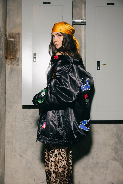 Person wearing a black jacket with colorful patches in an indoor setting