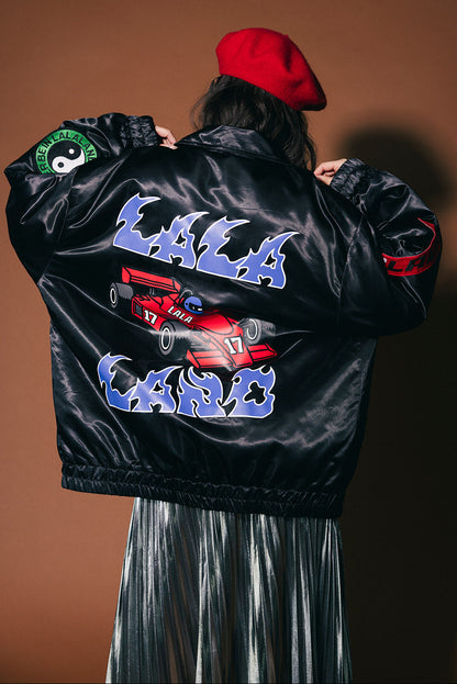 Person wearing a black jacket with colorful graphics and text on a brown background