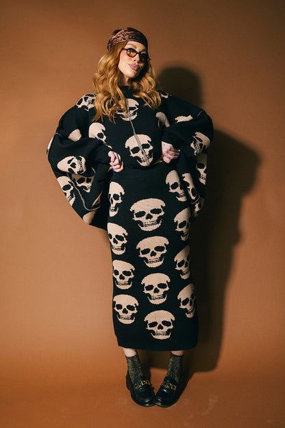 Person wearing a black knit skirt with skull pattern against a brown background