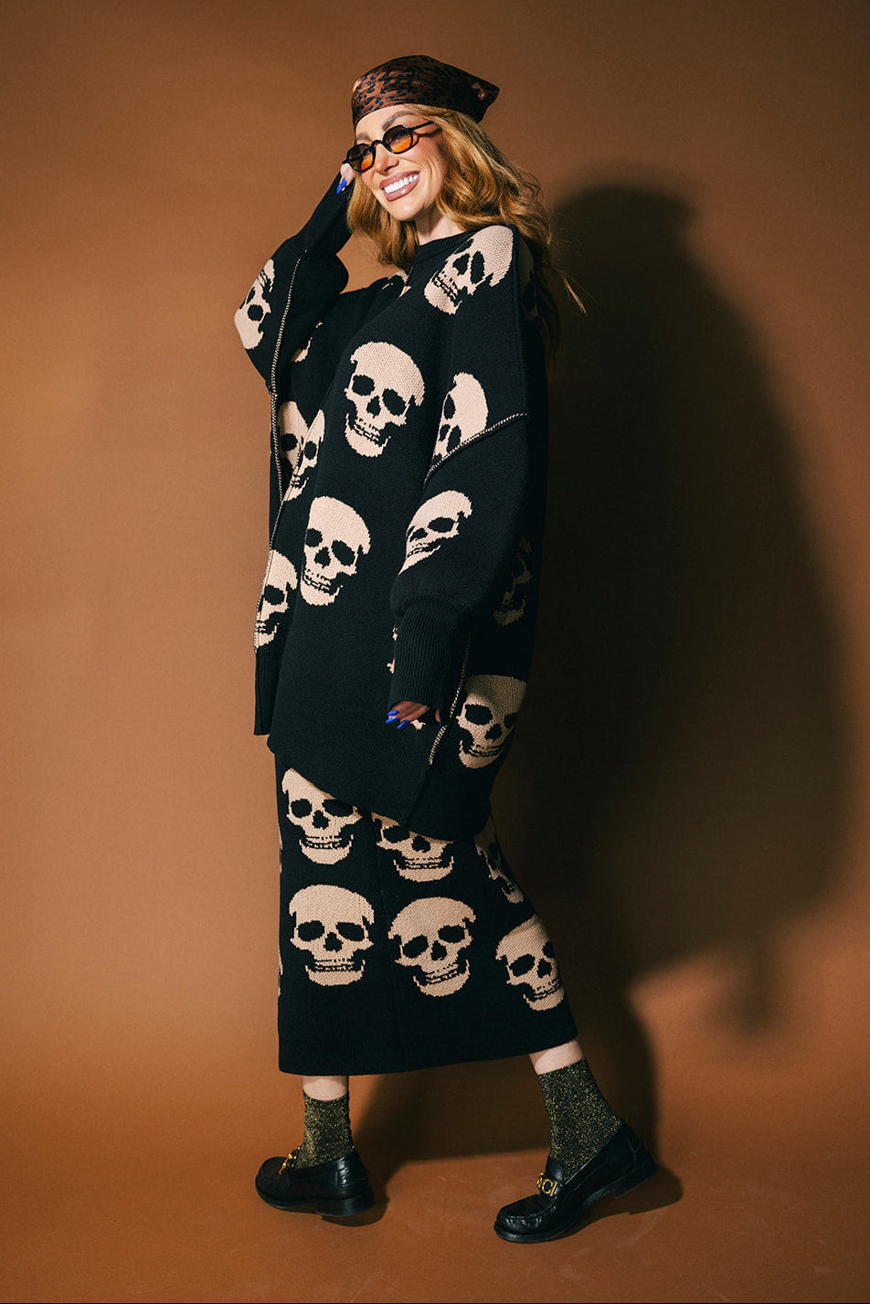 Person wearing a black knit skirt with skull pattern against a brown background