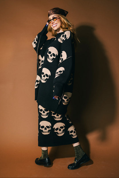 Person wearing a black knit skirt with skull pattern against a brown background