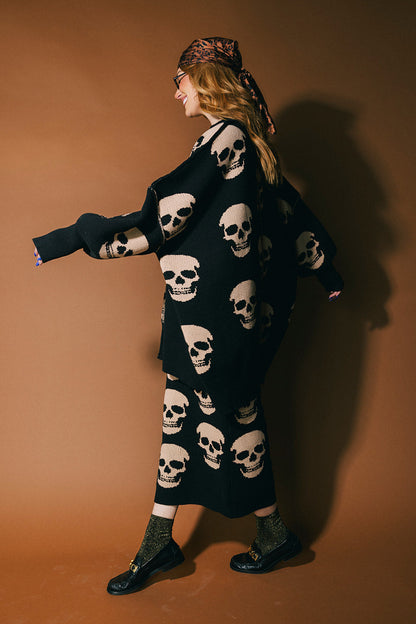 Person wearing a black knit skirt with skull pattern against a brown background