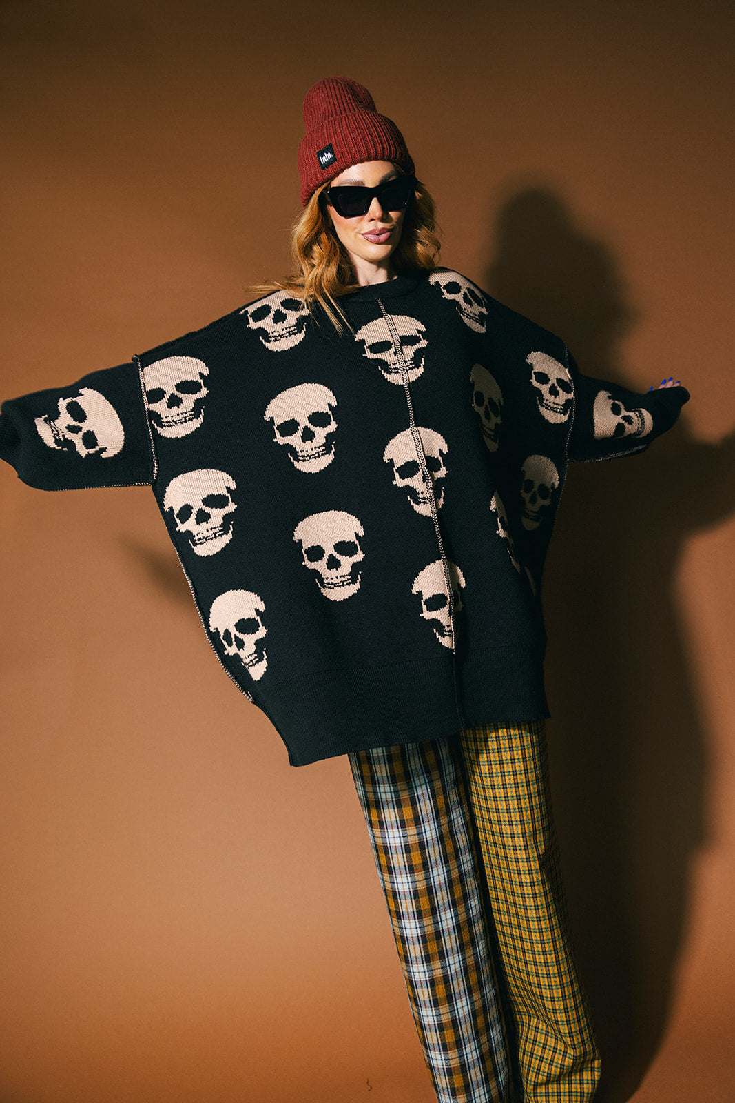 Person wearing a black skull-patterned sweater with a brown background