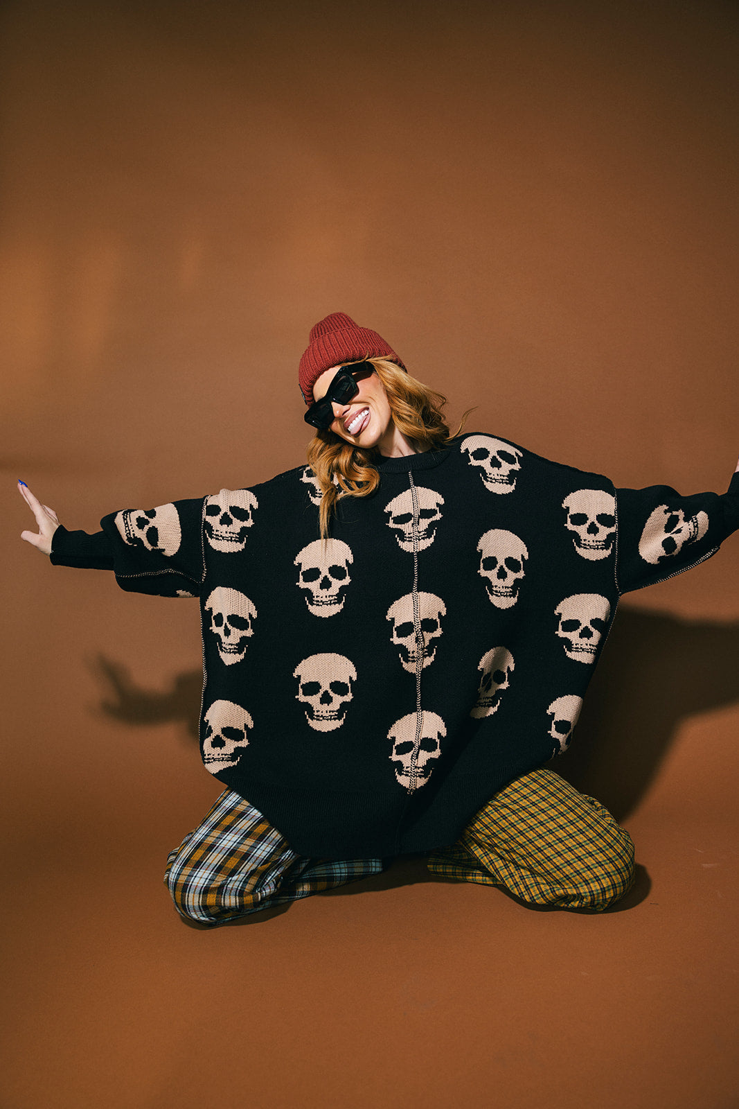 Person wearing a black skull-patterned sweater with a brown background