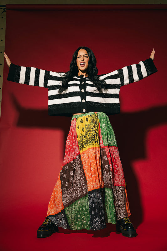 Person wearing a patchwork style bandana print pleated midi skirt on a red background