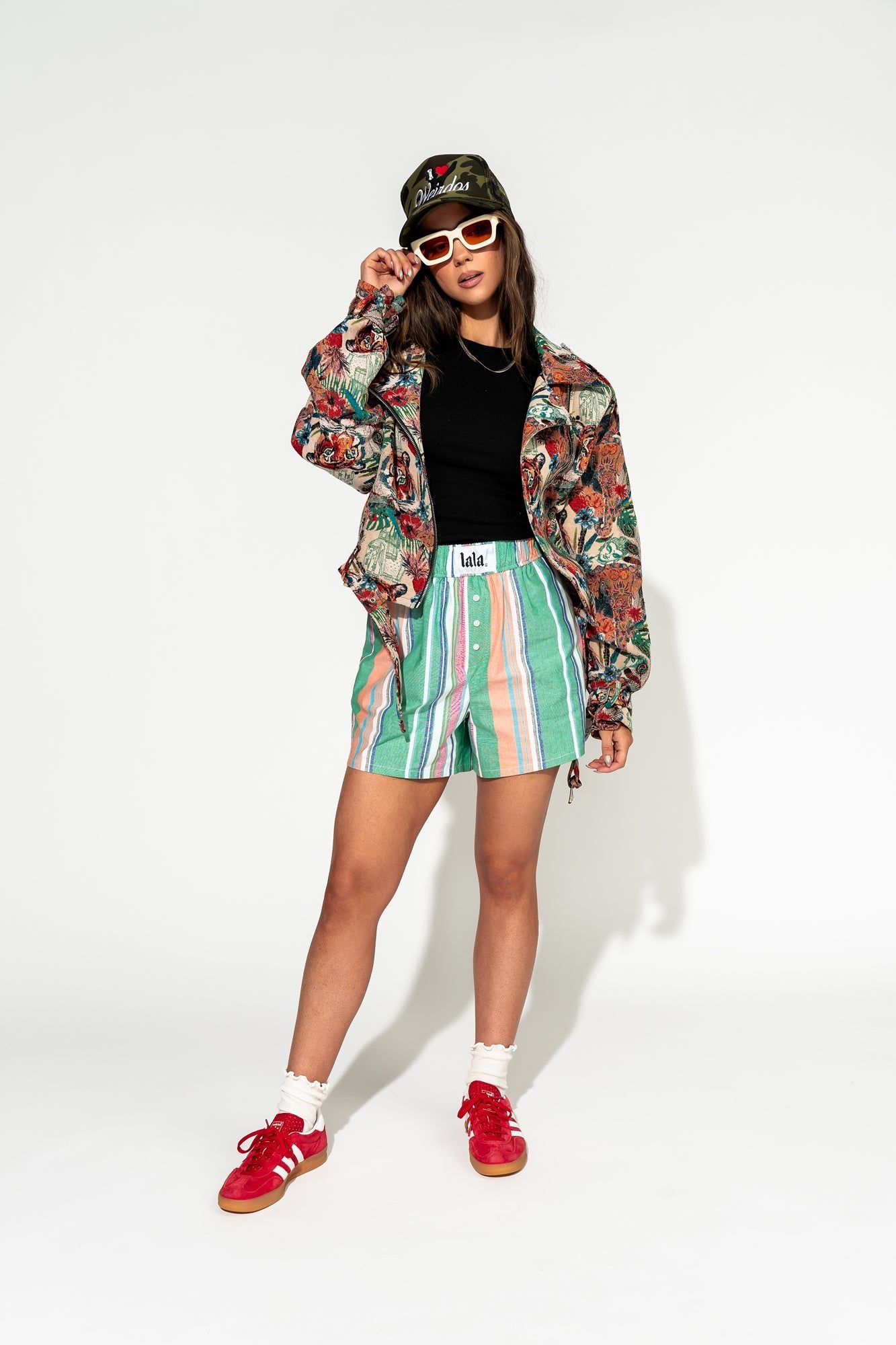 photo of girl wearing multi color stripe boxer shorts with elastic waistband with white label that says "lala" in the front, 3 button faux fly, and side pockets