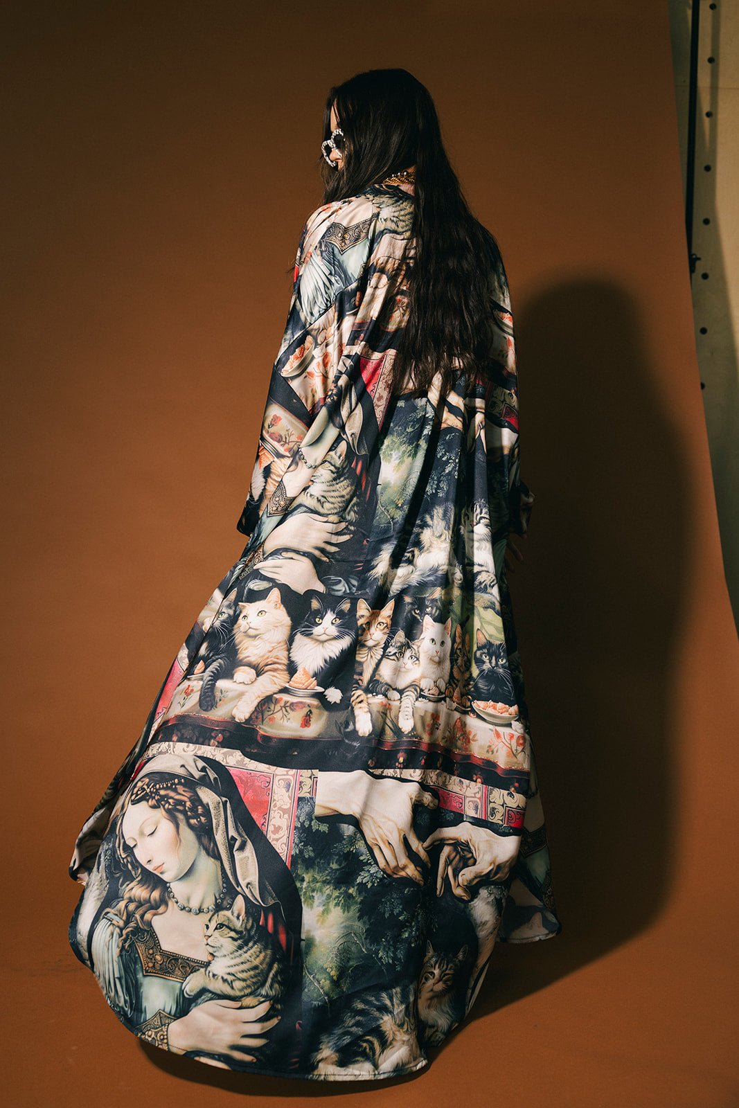 Woman wearing a renaissance cat pattern satin duster against a brown background.
