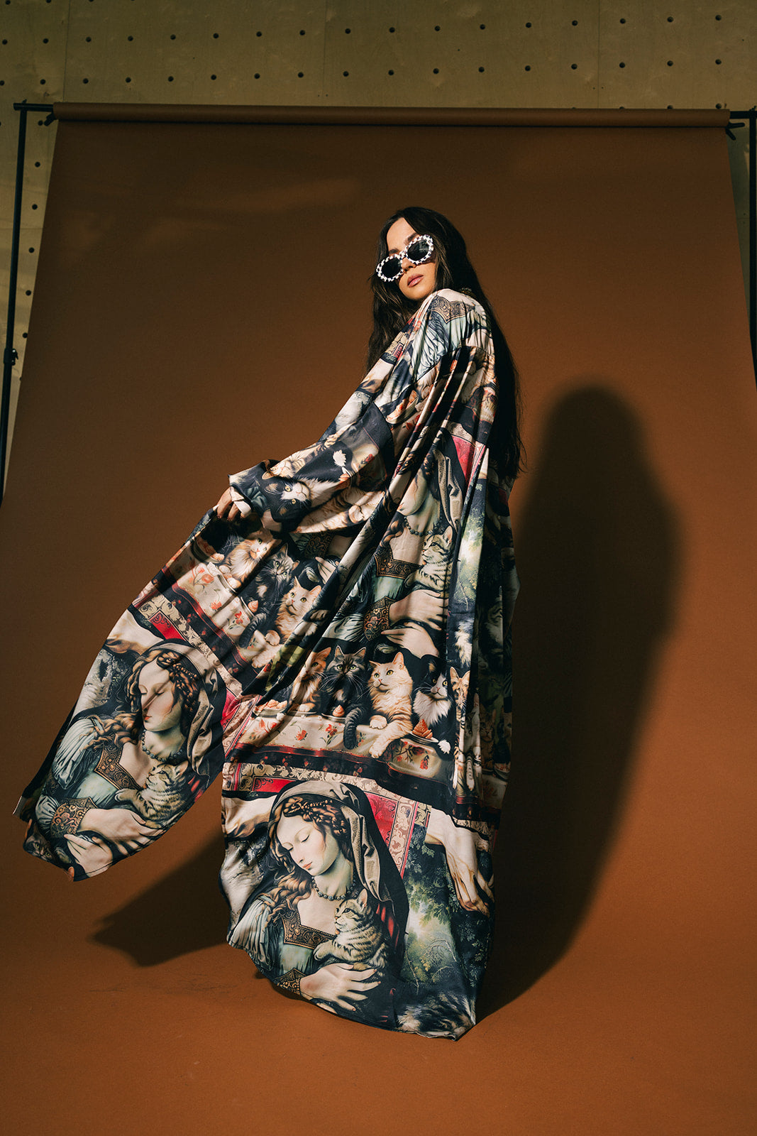 Person wearing a long, cat renaissance pattern satin duster against a brown background