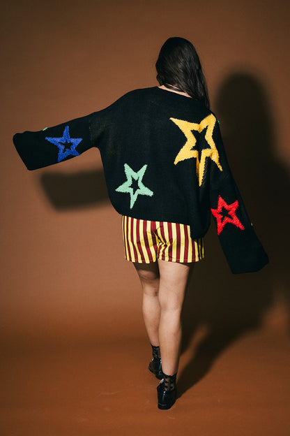 Person wearing a black sweater with colorful star patterns on a brown background