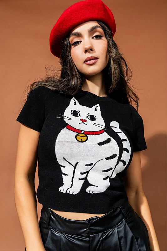 Woman wearing a black t-shirt with a cat graphic and a red beret against a brown background