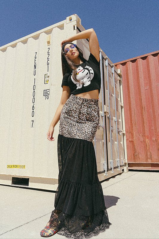 Person posing in front of shipping containers with a clear blue sky.