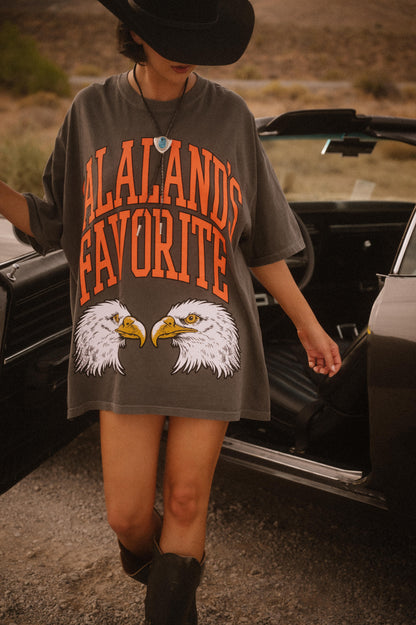 Person wearing a t-shirt with eagle graphics, standing next to an open car door.