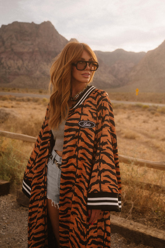 Person wearing a tiger-striped robe with a logo in a desert setting