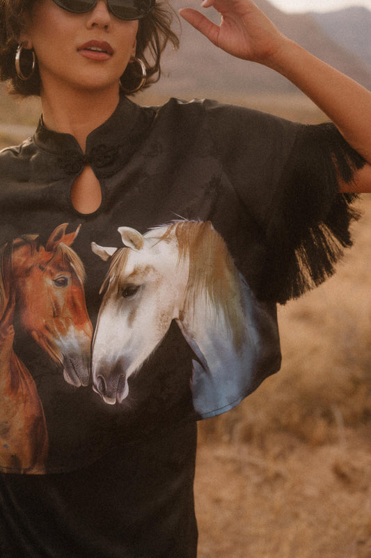 Woman wearing a black t-shirt with horse design in a desert setting
