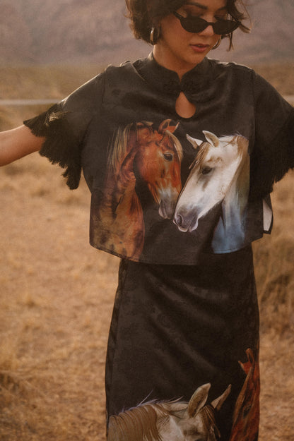 Person wearing a black t-shirt with horse graphics in a desert setting