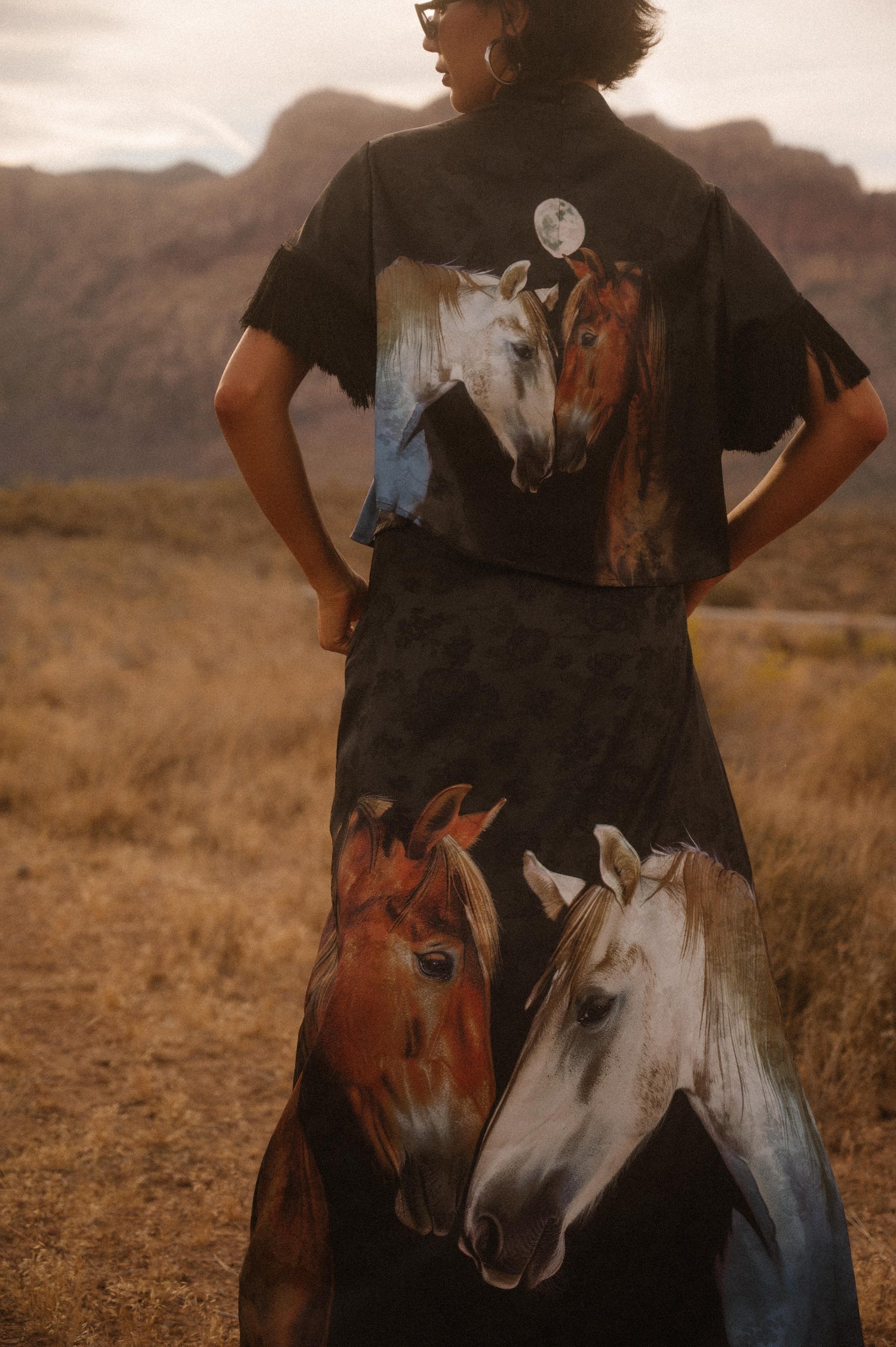Person wearing a shirt with horse designs in a desert landscape